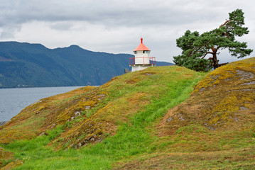 Fototapeta na wymiar Lighthouse in Norwegian fjords mountain picturesque landscape. Norway