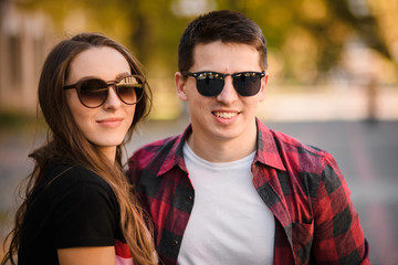 Happy couple in the sunglasses standing in the autumn park