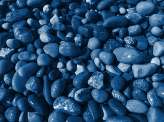 Sea pebbles toned in deep classic blue color, abstract trendy background
