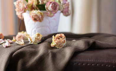 Obraz na płótnie Canvas Dried roses on brown scarf. Faded flowers