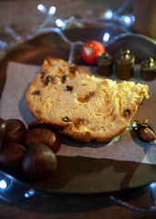 Selective focus, a panettone slice, tradition in brazilian christmas. Portuguese chestnut. Dark aged wood background, defocus lights, white color. Seen from above. Vertical