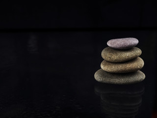 Spa Stones. black shiny zen stones with water drops over black background. Zen stones pile in raindrops, concept of calm, peace