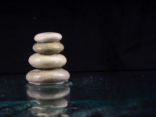 Spa Stones. black shiny zen stones with water drops over black background. Zen stones pile in raindrops, concept of calm, peace