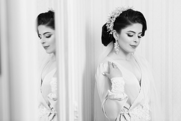 Close up portrait of beautiful bride standing. Charming bride in robe. Wedding hairstyle, style and makeup for the celebration. Portrait of a young beautiful bride