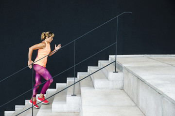 Young sporty woman dressed in sportswear running on stairs outdoors. Healthy Lifestyle
