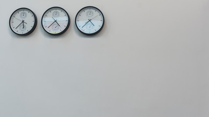 Three wall clocks showing time in different capitals of the world.