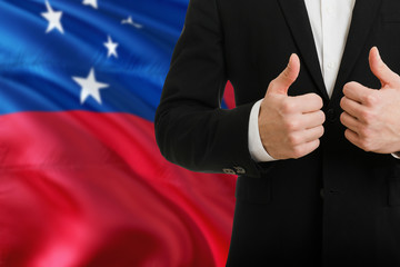 Samoa businessman showing thumbs up behind country flag with copy space. Successful international...