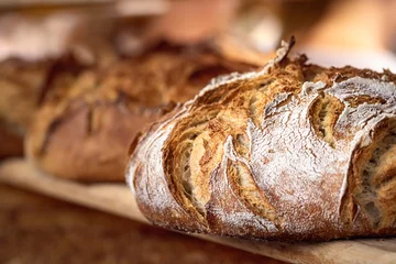Gordijnen Zuurdesembrood met knapperige korst op houten plank. Bakkerijproducten © YesPhotographers