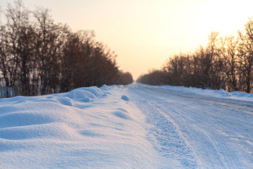 Fototapeta na wymiar Winter poorly cleared road. Road in the countryside strewn with snow. Winter landscape with snowdrifts