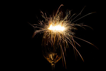 Three sparklers in a wine glass on a black