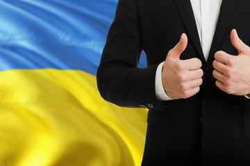Ukraine businessman showing thumbs up behind country flag with copy space. Successful international...