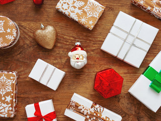Christmas presents on shabby wooden background. New Year gifts in white and golden paper with bright  ribbons.
