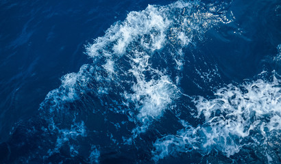 The undulating blue water of the ocean reflects the sky