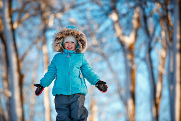 Cute little toddler girl wearing warm clothes playing on winter forest © levranii