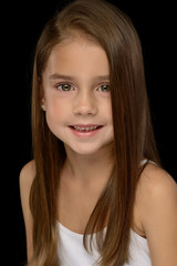 portrait of a little beautiful girl in a white T-shirt on a black background. Emotions