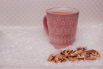 Pink cup of cocoa and chocolate in the snow