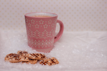 Pink cup of cocoa and chocolate in the snow