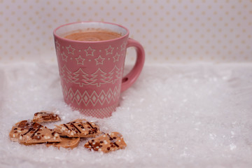Pink cup of cocoa and chocolate in the snow