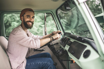 Waist up happy hipster man driving retro van