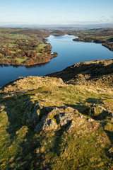 Obraz premium Beautiful Autumn Fall landscape of Ullswater and surrounding mountains and hills viewed from Hallin Fell on a crisp cold morning with majestic sunlgiht on the hillsides