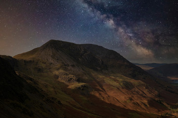 Stunning majestic digital composite landscape of Milky Way over Haystacks and High Stile in Lake District