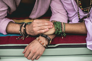 Hippie female and male tenderly holding hands