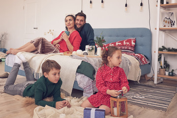 little boy girl having fun, friendship between siblings, family leisure time in living room. Children sister and brother playing drawing together on floor while young parents relaxing at home on sofa