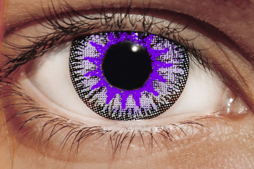 A closeup of an eye with large, bright blue lenses. Eyelashes and pupil close-up. Red hair and...