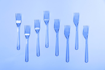 Fototapeta na wymiar Plastic fork pattern on classic blue background. Concept of color 2020.