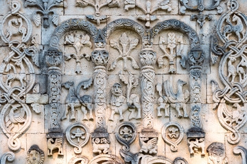Arched wall in church with carved characters.
