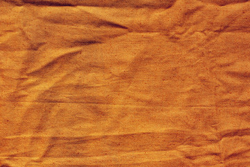 The texture of the fabric. Coarse, dense fabric in orange. The fabric is wrinkled.