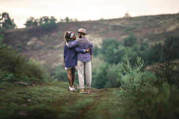 Stylish man and woman staying on nature hill
