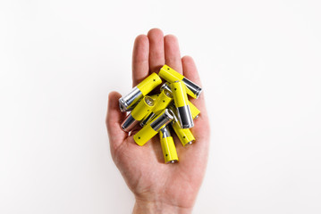 Man hand holding yellow alkaline batteries AA size, close up, isolated on white background with...