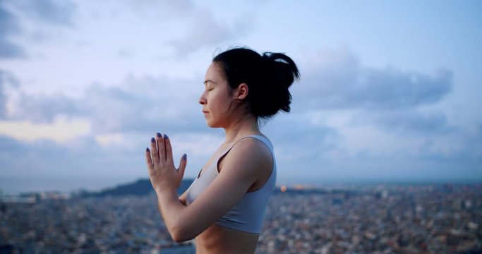 Feeling of calmness and freedom of beautiful female doing yoga asana at amazing urban spot, beautiful cloudy city view on background of young woman practicing meditation for mind relaxation wellness