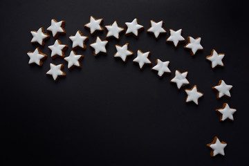 A big Christmas star made of many little biscuits in star shape, against a dark background with space for text