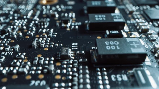 Macro Camera Moving Slowly over Printed Circuit Board, showing Computer Motherboard Components: Microchip, CPU Processor, Transistors. Inside of Electronic Device. Picture Becoming More Illuminated
