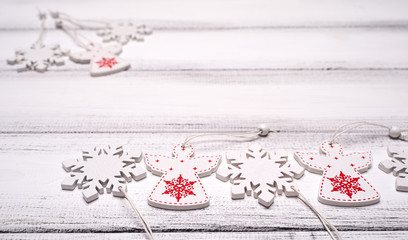 Red and white wooden snowflakes and angels for Christmas tree on white wooden table background