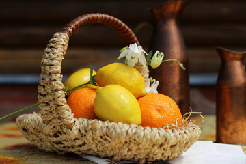 Oranges and lemons in wicker basket on table, rustic interior. Autumn mood. Fresh vitamins, sunny day