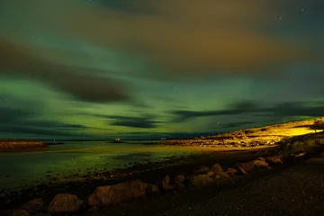 Foto op Aluminium Spectacularly beautiful green, blue and orange northern lights above a lake in Bourganes, with reflection in the water, in the foreground the beach, Iceland © Dasya - Dasya