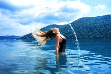 Beautiful girl splashing in the water. Retreat. Vacation. Colorful blue landscape. Rest, relax in...