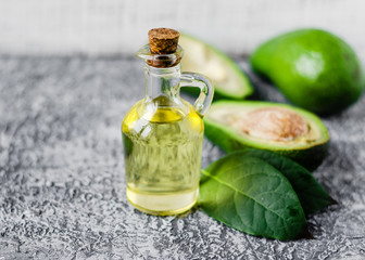 Avocado oil in a bottle and fresh avocado with leaf