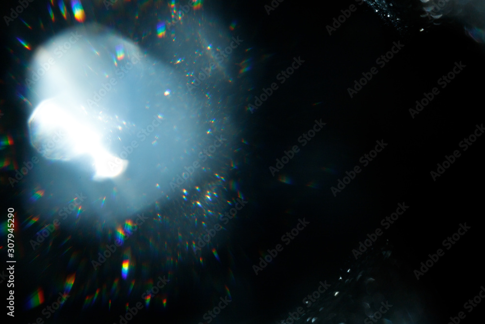 Poster Light over black background. Easy to add overlay or screen filter over photos. Abstract sun burst with digital lens flare background. Gleams rounded and hexagonal shapes, rainbow halo.