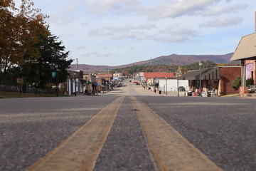 A street-level perspective view down a small town main street, Mena Street, Mena, Arkansas, with autumn colors on Rich Mountain in the background, small town America