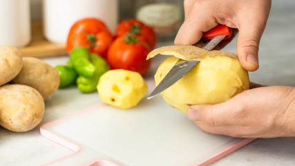 person slicing potato on cutting board for frying