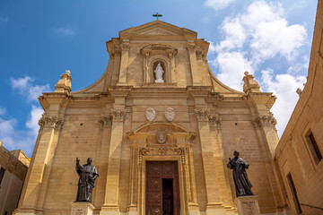 Fototapeta premium Facade of the Cathedral of the Assumption in the Cittadella of Victoria in Gozo, Malta. Cathedral is a fine baroque structure in the form of a Latin cross. It is built entirely from local limestone.