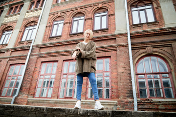 Blonde funny pretty girl near wall with red brick in Central part of old city. Portrait of girl on...