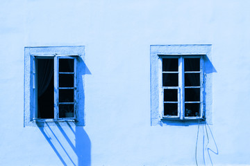 Two vintage windows on a white wall. Image is tinted in color Classic blue. Trend color 2020.