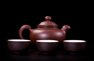 Ceramic tea cups and clay tea pot on a black background. Tea ceremony concept.