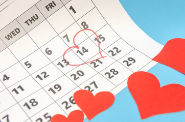 Valentine's day 14 is marked with a heart on the calendar, paper hearts are scattered around. Holiday concept