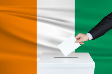 Election in Cote Dlvoire. The hand of man putting his vote in the ballot box. Waved Cote Dlvoire...